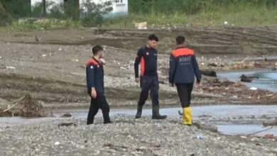 Fotoğrafta, su basmış bir alanda üç AFAD görevlisi arama çalışmalarına devam ediyor.