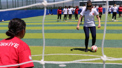 Görme engelli kadın sporcu, gözüne takmış olduğu siyah bant ile birlikte penaltı atışı yapıyor. Kadın sporcular futbol sahasında takım seçmelerine katılmak için arka tarafta kendi sıralarının gelmesini bekliyor.