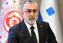 Çalışma ve Sosyal Güvenlik Bakanı Vedat Işıkhan, arkasında bakanlığa ait bayrak olan bir odada basın açıklaması yapıyor.