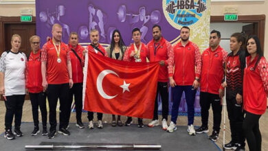 Görme engelli milli halterciler müsabakalar sonrasında kazandıkları madalyalarla birlikte, önlerinde Türk bayrağı açarak fotoğraf çekiliyorlar.
