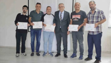 İşitme engelli kamu personeli olan bireyler ilk yardım eğitim sertifikasının dağıtım töreninde aldıkları sertifikalar ile kameraya doğru poz veriyorlar.