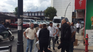 Fotoğrafta, yere düşmüş engelli bireyin başına kalabalık bir grup insan toplanmış. Engelli bireyin koltuk değneği ise yanında duruyor.