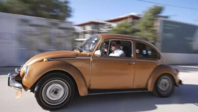 Kahverengi Vosvos türü bir otomobilde birkaç kişi var. Otomobil yolda hareket halindeyken özel bir teknik kullanarak çekim yapıldığı için yolun flu bir görüntüsü var.