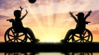 Görselde yer alan iki çocuk tekerlekli sandalyeleri üzerinde top atarak oyun oynuyorlar. Çocuklardan bir tanesi topu attığı için kolları havada diğeri de topu yakalamaya çalıştığı için kollarını açmış.