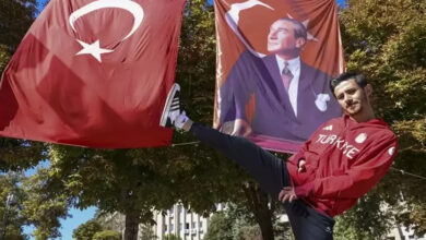 Para milli tekvandocu Mahmut Bozteke, tek ayağını havaya kaldırarak poz veriyor. Arkasında Türk bayrağı ve üzerinde Mustafa Kemal Atatürk olan bir başka bayrak daha asılı.