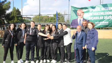Görme engelli kadın futbolcular, kupa etrafına toplanmış ve boyunlarına madalyaları takılmış şekilde fotoğraf çekiniyorlar.