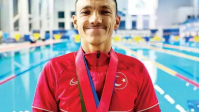 Paralimpik sporcu Umut Ünlü, havuzun kenarında boynundaki madalya ile birlikte fotoğraf için poz veriyor.