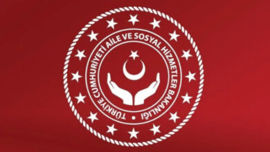 Fotoğrafta, Aile ve Sosyal Hizmetler Bakanlığı’nın logosu var. Logo kırmızı zemin üzerinde ilk halka burgulu bir görüntüsü var. Halkanın iç kısmında ve halka boyunca küçük birçok beyaz renkli yıldız var. Daha sonra ise iki düz beyaz halkanın içinde “Türkiye Cumhuriyeti Aile ve Sosyal Hizmetler Bakanlığı” yazısı var. Tam ortada ise yan tarafa doğru açılmış iki el, üstünde ise uçları yukarı doğru bakan bir ay ve onun da üstünde bir yıldız var.