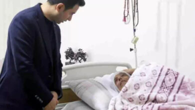 Genç İlçe Kaymakamı Muhammet Güzel, yatakta yatan engelli bir bireyin başında onunla sohbet ediyor.