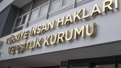 Fotoğrafta, bir binanın dış mekan görüntüsü var. Binanın üzerinde asılı olan tabelada gri zemin üzerine, sarı renkle ve büyük puntolarla “Türkiye İnsan Hakları ve Eşitlik Kurumu” yazısı var.