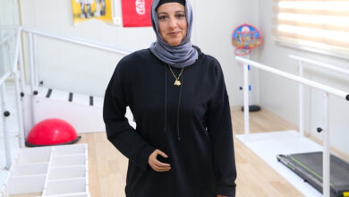 Fotoğrafta, fizik tedavi odasında ayakta duran engelli birey Gülcan Yılmaz var.