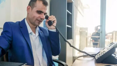 Görme engelli bireyi Mehmet İpek, masanın üzerinde duran telefonun ses giden başlığını kulağına doğru tutarak telefondaki kişiyle konuşuyor.