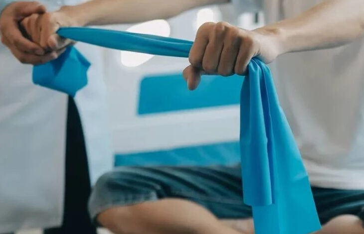 Fotoğrafta, elinde mavi bir bez tutan belden aşağısı görselde yer alan bir kişi ve yanında belden aşağısı gözüken beyaz önlüklü bir doktor var.