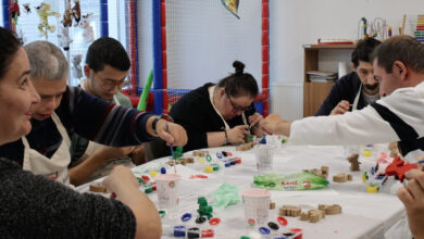 Engelli bireyler bir masanın etrafında oturmuş Lego oyuncaklarını birleştirerek çeşitli şekiller elde ediyorlar.