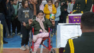 Fotoğrafta, tekerlekli sandalye kullanan engelli bir kız çocuğu bando takımını yönetiyor.