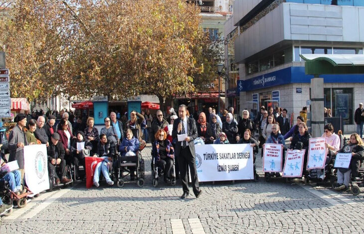 Fotoğrafta, Türkiye Sakatlar Derneği İzmir Şubesinin düzenlemiş olduğu basın açıklamasına katılan engelli bireyler ve aileleri yer alıyor.