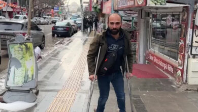 Van Engelliler Derneği Başkanı Hanifi Baykara, fotoğrafta bir kaldırım kenarında koltuk değnekleri ile ayakta duruyor.