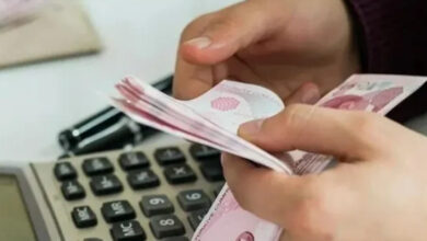 Fotoğrafta, sadece elleri gözüken bir kişinin 10 TL'lik kağıt paraları saydığı görülmektedir. Aynı zamanda fotoğrafta yer alan masada hesap makinesi, kalem var.