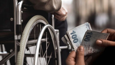 Fotoğrafta, tekerlekli sandalye kullanan engelli birey ve fotoğrafın sağ alt köşesinde ise para sayan bir el var.