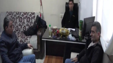 Görme engelli bireyler bir odanın içerisinde oturuyor ve beyaz bastonları duvara yaslanmış şekilde duruyor.