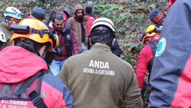 Fotoğrafta, arama kurtarma ekipleri bir kişinin cesedini bulmuş ve taşıyorlar.
