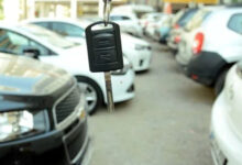 Fotoğrafta, bir araba galerisinde yan yana duran iki sıra halinde otomobiller var. Fotoğrafı çeken kameranın tam önünde ise bir otomobil anahtarı yukarıdan aşağıya doğru sallanarak duruyor.