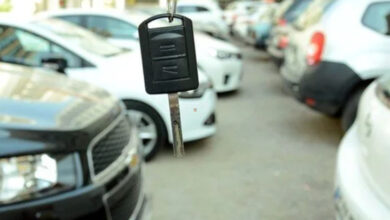 Fotoğrafta, bir araba galerisinde yan yana duran iki sıra halinde otomobiller var. Fotoğrafı çeken kameranın tam önünde ise bir otomobil anahtarı yukarıdan aşağıya doğru sallanarak duruyor.