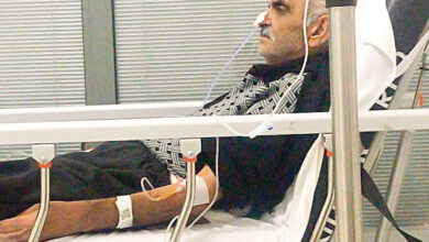 Fotoğrafta, hastanede tedavi gören Ahmet Okçu, hasta yatağında yatıyor ve bazı kablolar ile oksijen desteği veriliyor.