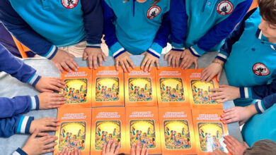 İlkokul öğrencileri proje kapsamında yazmış oldukları kitabı masanın üzerine katarak etrafında duruyorlar.