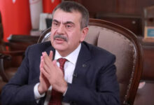 Milli Eğitim Bakanı Yusuf Tekin fotoğrafta tahta eski tip bir koltukta oturuyor. Ellerine yüzünün biraz önünde birleştirerek kendinden emin bir görüntü vermeye çalışıyor.