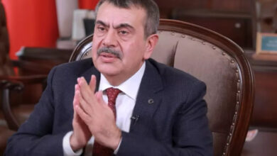 Milli Eğitim Bakanı Yusuf Tekin fotoğrafta tahta eski tip bir koltukta oturuyor. Ellerine yüzünün biraz önünde birleştirerek kendinden emin bir görüntü vermeye çalışıyor.