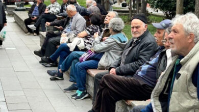 Fotoğrafta, bir parkta yan yana oturan yaşlı bireyler var. Yaşlı bireyler parkta oturarak zaman geçiriyor.