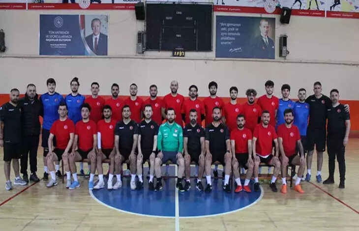 Görselde, kırmızı ve siyah formalar giymiş bir grup erkek sporcu ve teknik ekip, bir spor salonunda toplu halde poz veriyor. İşitme Engelli Erkek Futsal Milli Takımı’nın, Sırbistan'daki Avrupa Şampiyonası eleme maçları için Aksaray'da yaptığı hazırlıkları yansıtan bir kare.