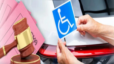 Görselde, bir kişi beyaz bir aracın arkasına engelli park kartı sembolü yapıştırıyor. Sol tarafta bir hakim tokmağı ve pembe renkli dava dosyaları bulunuyor.