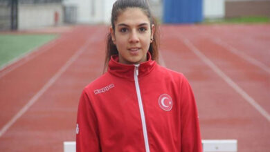 Özel Milli Sporcu Esra Bayrak, milli takım üniforması ile tartan pistte poz veriyor.