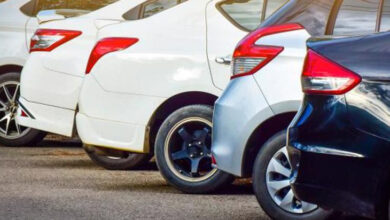 Fotoğrafta, bir otoparkta arka arkaya park edilmiş farklı renklerde otomobiller görülüyor. Araçların arka kısımları ve far detayları dikkat çekiyor. Beyaz, gümüş ve siyah renklerdeki araçlar, modern tasarıma sahip.