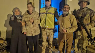 Görselde, gece saatlerinde çekilmiş bir fotoğrafta, bir grup insan bir evin önünde poz veriyor. Ortada, zihinsel engelli olduğu belirtilen genç bir birey kamuflaj desenli bir mont giymiş halde duruyor. Yanında bir kadın ve yaşlı bir adam bulunuyor. Sağ ve sol tarafta ise jandarma personeli yer almakta; biri reflektörlü bir yelek giymişken, diğeri tam teçhizatlı bir asker olarak dikkat çekiyor.