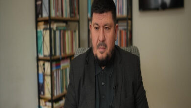 Görselde, görme engelli hafız Bülent Acun yer alıyor. Kendisinin analog kasetçalardan dinleyerek ezberlediği Kur’an-ı Kerim’i aynı yöntemle tazelediği belirtiliyor. Ayrıca, el yazısıyla kaleme aldığı kitaplarıyla da dikkat çekiyor. Arka planda kitaplıklar ve bir televizyon ekranı bulunuyor. Bu, onun bilgiye olan bağlılığını ve hafızlık konusundaki özel yöntemlerini vurgulayan anlamlı bir kare.