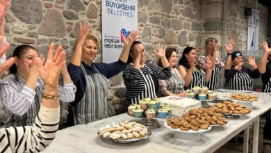 Görselde, İzmir Büyükşehir Belediyesi Meslek Fabrikası'nda düzenlenen bir pastacılık kursunun sonunda çekilmiş neşeli bir an yer alıyor. Taş duvarlı bir mekânda önlerinde çeşitli tatlılar (kurabiyeler, kekler, pasta) bulunan kursiyerler, mutfak önlükleriyle ayakta duruyor ve ellerini havaya kaldırarak kutlama yapıyorlar. Kursa katılanlar arasında kadınlar ağırlıkta.