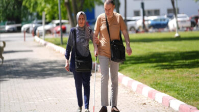 Anne Nevra Yıldırım, beyaz baston kullanan oğlu Önder Savaş Yıldırım ile sokakta kol kola yürüyor.