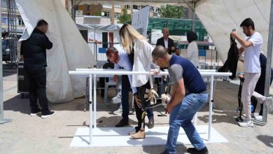Fotoğrafta, yürüme parkurunda ayağına takmış olduğu cihaz ile yürümeye çalışan bir kadın var.