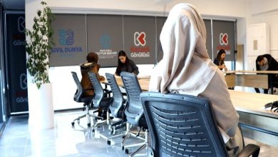 Kapalı bir alanda birkaç kişinin bazı evrak reformları doldurduğu görülmektedir. Ayakta yer alan bir kişide destek amacıyla ihtiyaç duyan kişilere yardımcı oluyor.