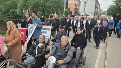 Bu görselde, 10-16 Mayıs Engelliler Haftası kapsamında Bartın'da düzenlenen bir yürüyüş etkinliği görülmektedir. Ön saflarda akülü tekerlekli sandalye kullanan bireyler yer almakta, arkalarında ise çeşitli yaş ve cinsiyetlerden katılımcılar yürümektedir. Katılımcılar arasında Bartın Belediyesi ve dernek üyeleri de bulunmaktadır.