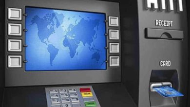 Görselde bir ATM cihazı yer alıyor. Ekranında mavi tonlarda bir dünya haritası görüntülenmiş. Ekranın her iki yanında işlem tuşları bulunuyor. Alt kısımda ise rakam tuş takımı, renkli işlem tuşları (iptal, düzelt, giriş) yer almakta. Sağ tarafta kart giriş yuvasında mavi renkli bir banka kartı takılı duruyor. Ayrıca "RECEIPT" (fiş) ve "CARD" (kart) bölümleri de etiketlenmiş şekilde görülüyor. Görsel, muhtemelen erişilebilirlik özelliklerine sahip yeni nesil ATM'leri temsil ediyor.