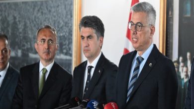 Görselde, resmi bir basın toplantısı ya da açıklama anı yer alıyor. Sağda yer alan kişi konuşma yaparken görülüyor ve önünde çeşitli basın kuruluşlarına ait mikrofonlar (TRT, DHA, A Haber vb.) bulunuyor. Sağlık Bakanı Kemal Memişoğlu’nun konuştuğu an olabilir. Diğer kişiler ciddi yüz ifadeleriyle onu dinliyor. Arka planda Türk bayrağı ve tarihi bir fotoğraf dikkat çekiyor.