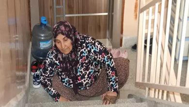 Fotoğrafta, Hatice Avcı isimli engelli birey eline geçirmiş olduğu terliklerle birlikte merdivenler yukarı doğru sürünerek çıkmaya çalışıyor.