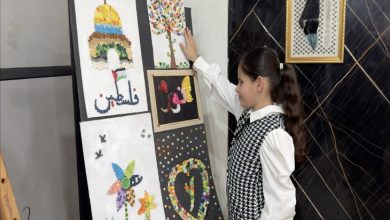 Fotoğrafta, görme engelli bir kız çocuğu resim tablolarının önünde durmuş ve tablolara dokunarak basın mensupları ile konuşuyor.