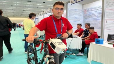 Muhammed Emir Ünalan, yapay zeka destekli bisikleti tutarak poz veriyor.