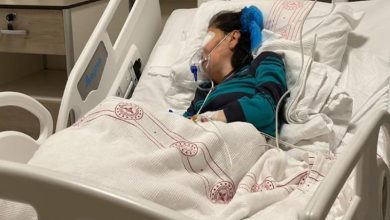 Bakım merkezinde saldırıya uğrayan kadın hastane yatağında gözleri sargılı ve oksijen maskesi takılı şekilde uzanıyor.