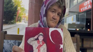 Fotoğrafta yaşlı bir kadın, duygusal bir ifadeyle elinde genç bir askerin fotoğrafını tutuyor. Kadın başörtülü, hüzünlü ve yorgun bir yüz ifadesine sahip. Tuttuğu fotoğrafta, Türk bayrağı fonu önünde selam veren bir genç asker yer alıyor. Mekân, bir sokak kenarındaki açık bir oturma alanı gibi görünüyor; arka planda bir "oto yıkama" tabelası dikkat çekiyor.